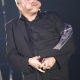 Steve Rawlings, de traje oscuro y con un sombrero en las manos, durante un número cómico.