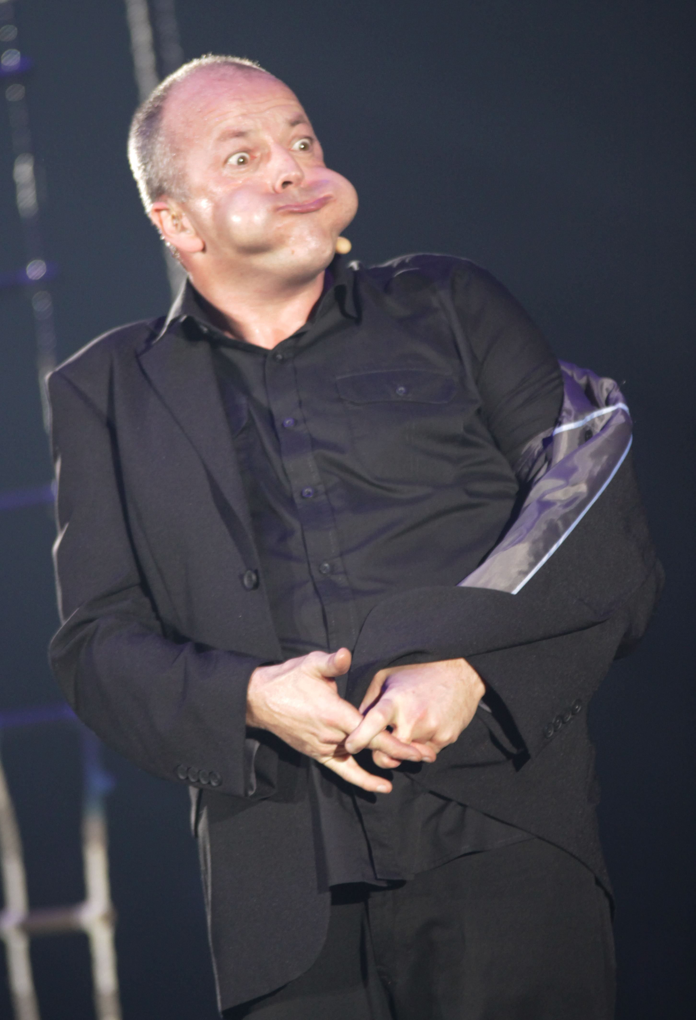 Steve Rawlings, de traje oscuro y con un sombrero en las manos, durante un número cómico.